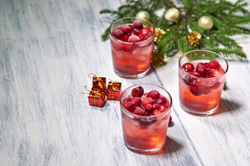 Glasses with cranberry juice on white wooden background with pine branch in the background. Christmas tre. Copy space