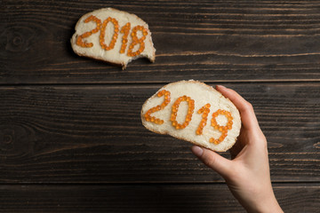 Woman holding red caviar 2019 sandwich with 2018 sandwich bitten on the background