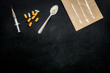 Take drugs, drugs addiction concept. White powder like heroine or cocaine, drug tracks pills, spoon, syringe on black background top view copy space