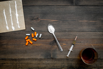 Take drugs, drugs addiction concept. White powder like heroine or cocaine, drug tracks pills, spoon, syringe on dark wooden background top view copy space