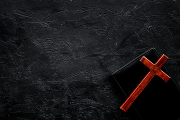 Farewell ceremony, funeral concept. Wooden cross on Bible on black background top view space for...