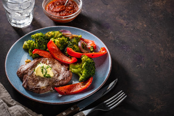 Grilled Beef steak with garlic butter and vegetables. Meat with grilled bell pepper, broccoli and onions.