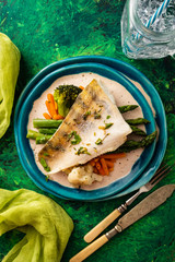 Pike perch fillet with asparagus, broccoli and carrots. Fried fish with stewed greens