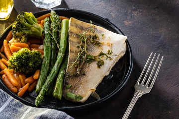 Pike perch fillet with asparagus, broccoli and carrots. Fried fish with stewed greens