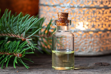 A bottle of spruce essential oil with fresh spruce branches
