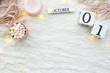 Perpetual calendar 1 october. Warm cozy winter autumn concept. Mock up on cozy fur fluffy white background with lights garland, candle,laptop and cocoa .