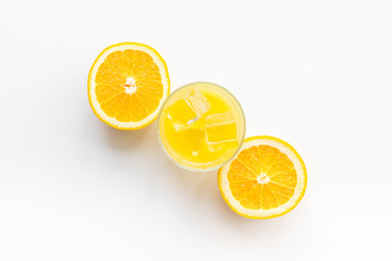Glass of cold orange juice near halfs of fresh oranges on white background top view pattern copy space