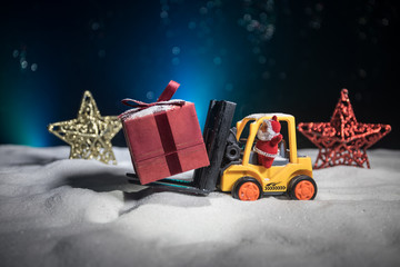 Miniature Gift Box by Forklift Machine on snow ,Determined Image for Christmas Holiday and Happy New Year Gift Celebration concept.