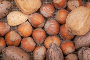 Macro shot of different nuts: almond, walnut, hazelnut and pecan on burlap background.