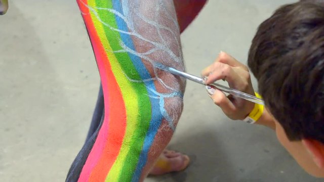 Body art close-up. Creating drawing on the skin of body person with colorful paints and brush. Artistic creation creativity