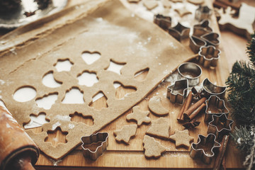 Christmas gingerbread cookies dough with metal cutters on rustic table with wooden rolling pin, cinnamon ,anise, cones, christmas decorations. Atmospheric stylish image, winter holidays
