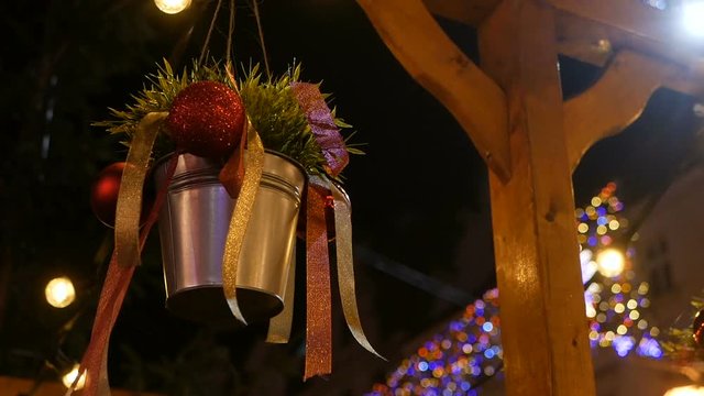 New Year decoration bucket with ribbons and Christmas balls, hunging retail trade at christmas fair on street. new year street decorations and glowing garlands