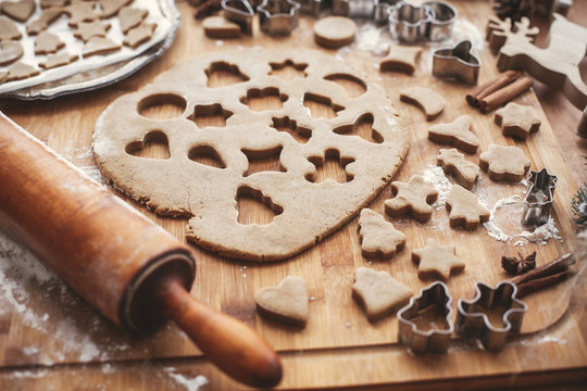 Gingerbread dough with metal cutters for christmas cookies on rustic table with wooden rolling pin, cinnamon ,anise, cones, christmas decorations. Atmospheric stylish image