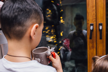 Children stand on the background of the New Year's window and look through a window to the street