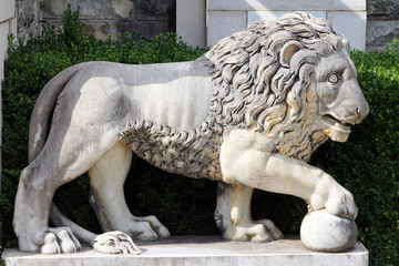 Marble lion with a ball - ancient sculpture in the park of Peles Castle, Sinaia, Romania