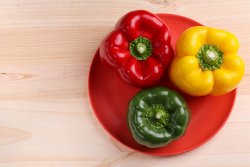 three sweet peppers, wooden table background