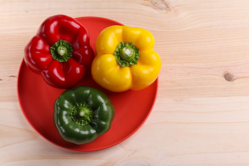 three sweet peppers, wooden table background