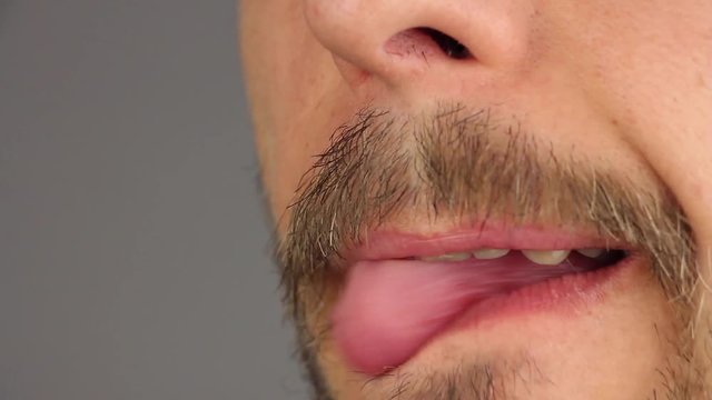 man with mustache licks his lips by tongue, two times, side view, closeup macro 
