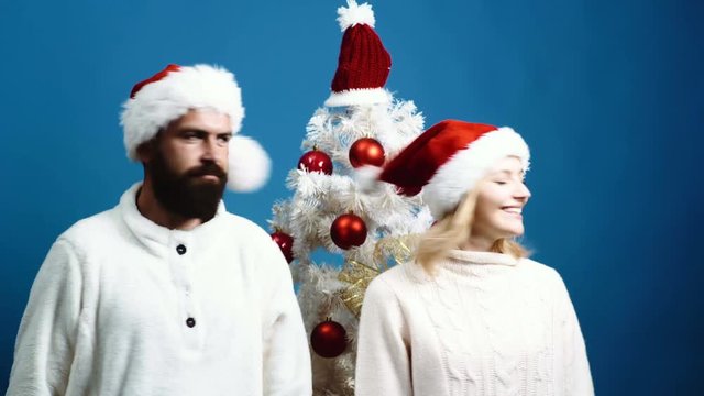 Man and Woman in New Year's hats are having fun at the Christmas tree. Concept of celebrating new year and Christmas.