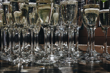 Sommelier pours champagne from a bottle into a glass at the table in the restaurant.