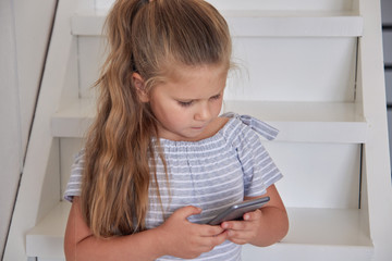 Girl using phone on stairs at home