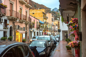 Fototapeta na wymiar View of pedestrian street and road at Giardini Naxos town in rainy weather. Taormina, Sicily, Italy