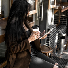 Beautiful girl drinks coffee, sitting in a cozy cafe.