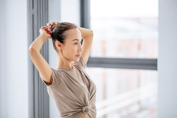 young awesome woman ddoing a hairbun before yoga classes. close up side view photo.