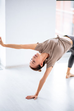 Young sporty emotional woman dancing in the studio , Wild Thing pose, Flip-the-Dog exercise, Camatkarasana. close up cropped photo