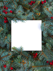 Layout made of Christmas tree branches, red berries and paper card note. Mockup, flat lay. New Year winter season concept