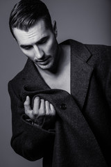 Fototapeta na wymiar Black&white portrait of handsome shirtless young man in a coat. Perfect hair & skin. Close up. Studio shot