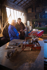 Fototapeta na wymiar A senior man and his son at workshop to restore an old pedal car