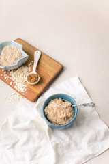 Fototapeta na wymiar Oatmeal Porridge in a Blue Bowl with Raw Oats and Brown Sugar in Background