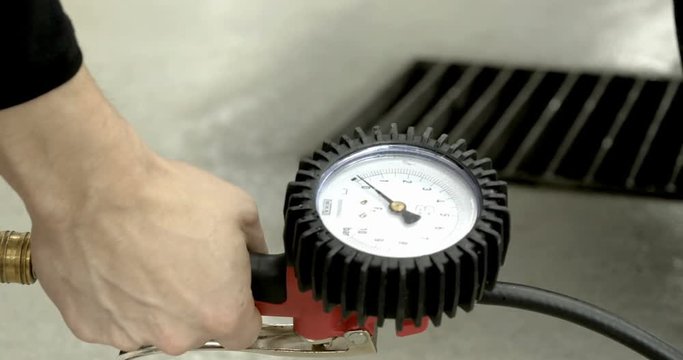 A professional worker in a service station checks (pumps) the pressure of the wheels of a car. Concepts from: Car, Pressure Sensor, Tech Service.