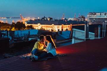 Fototapeta na wymiar Loving couple is sitting on the roof of the house. Beautiful evening