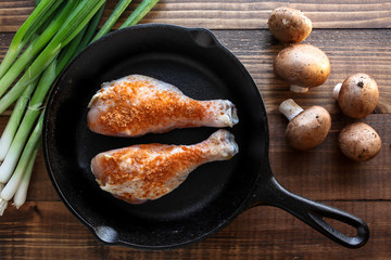 Chicken, scallions and mushrooms  on baking pan with wooden background