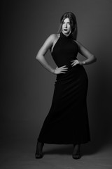 Cute blonde woman in gorgeous, elegant dress.Posing on grey backgorund.Black and white.Studio.