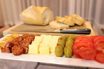 Plate of beautifully arranged apero bites with sliced bread in the background.