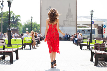 Young brunette woman in summer red dress on street background