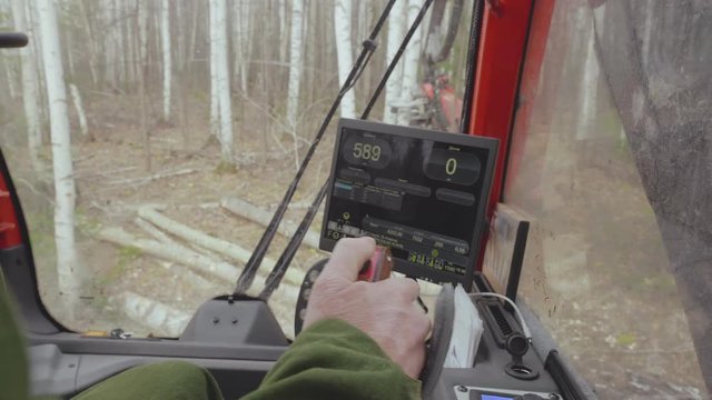 View from driver&rsquo;s cab of worker&rsquo;s hand is controlling the agricultural machine
