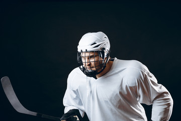 Isolated shot of ice-hockey player in white sportswear and white helmet holding hockey stick...