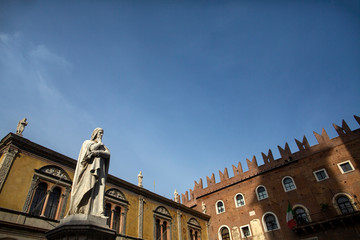 Fototapeta na wymiar Statue of Dante Alighieri in Piazza dei Signori, Verona, Italy. Beautiful statues of Dante in the middle of Verona old town with other sculptures and architecture. Summer day in Verona
