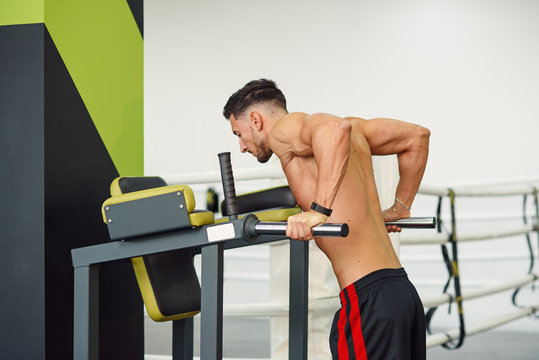Close up shot of sporty fitness man doing push-ups on parallel bars while training in modern gym. Healthy and sporty concept.