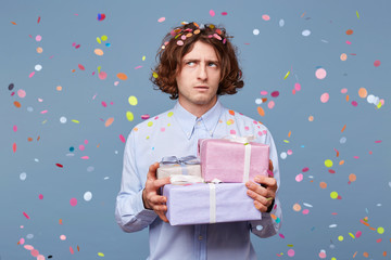 Birthday man accepts congratulations, holds gifts from guests, looks puzzled away, tries to recall something, little confused