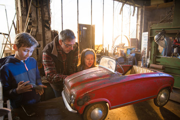 Father and his young childs at workshop, restoring a pedal car