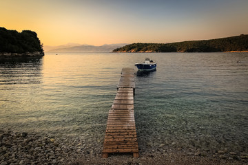 View of the bay at sunset, (golden hour) stony beach with a small jetty to which the boat was moored,