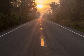 Asphalt road with sun rising in the countryside.