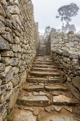 Fototapeta na wymiar Following the Inca steps in the streets paths inside the famous travel destination: Machu Picchu citadel just an amazing representation of the Inca Empire the Lost City in the Andes on a foggy day