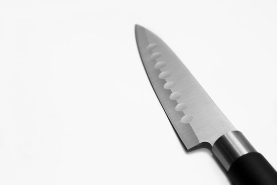 Kitchen steel sharp knife with a black handle on a gray background. Side view. Close-up