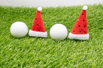 Golf balls with Santa hats are on green grass for golfer Christmas